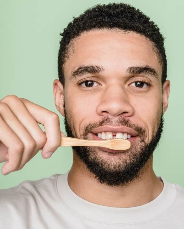 man with gapped teeth brushing teeth